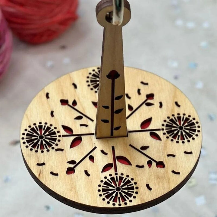 "Modern trähållare för garn i minimalistisk design, visar flera garnrullar i olika färger på en stabil träbas."