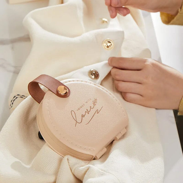 "Multifunktionell handhållen sömnadssats i beige och grön med nålar och trådar i en kompakt, lätt design."