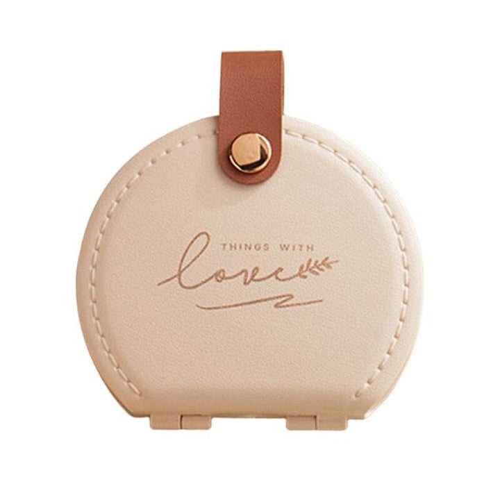 "Multifunktionell handhållen sömnadssats i beige och grön med nålar och trådar i en kompakt, lätt design."