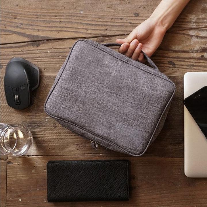 "Multifunktionell kabelförvaringspåse i vattentätt tyg med nätfickor, elastiska öglor för kablar och tillbehör."