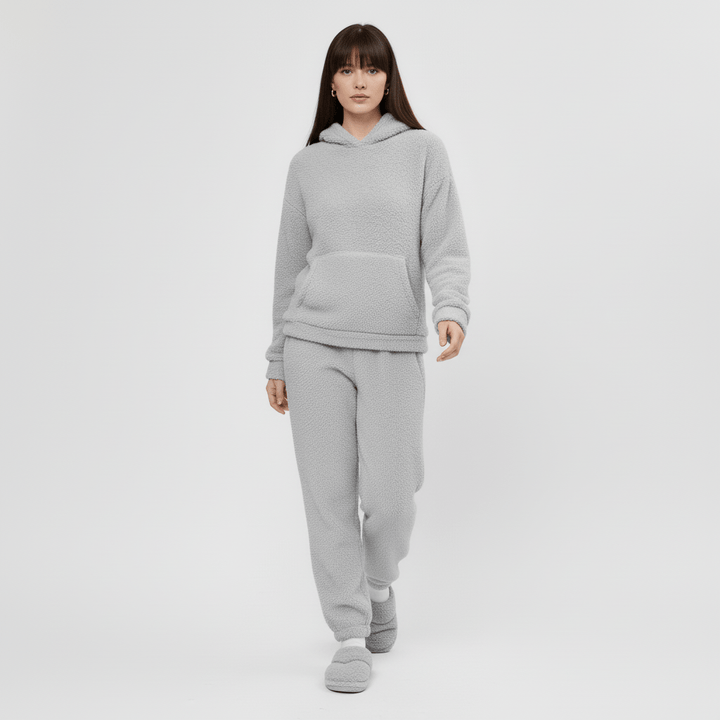 Dam i Skye loungewear-set med känguruficka, poserar bekvämt. Avslappnad look.