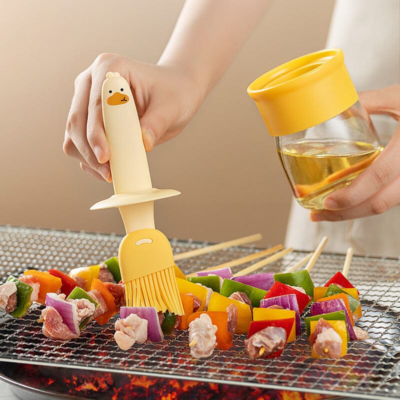 "Oljedispenser med söt ankformad silikonborste för grill, i beige och orange, perfekt för matlagning."