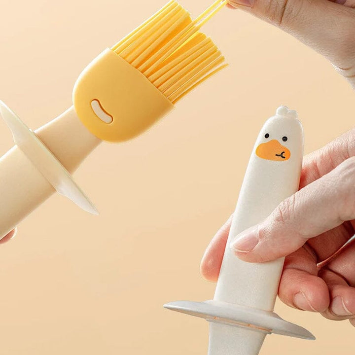 "Oljedispenser med söt ankformad silikonborste för grill, i beige och orange, perfekt för matlagning."