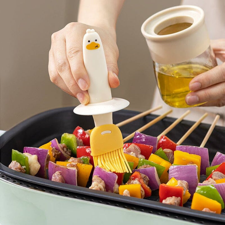 "Oljedispenser med söt ankformad silikonborste för grill, i beige och orange, perfekt för matlagning."
