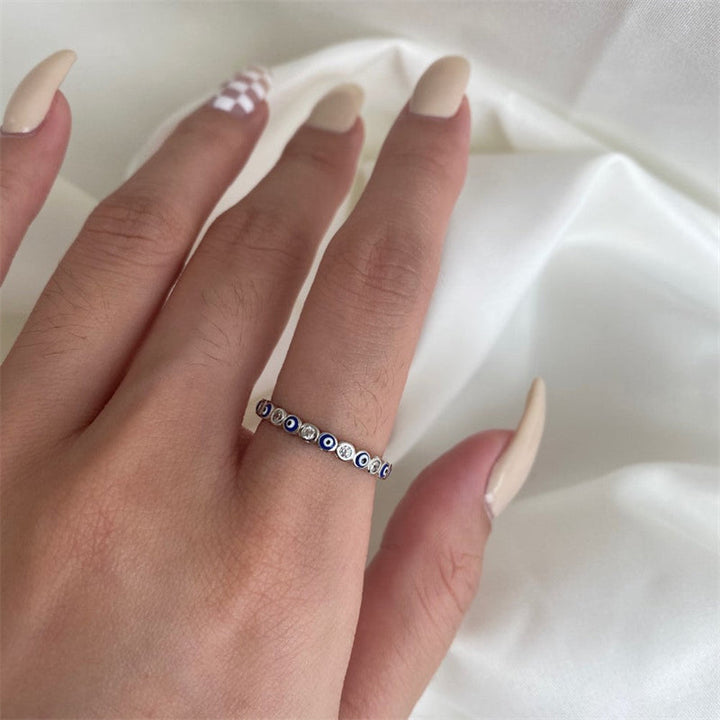 "Onda Ögat Zirkonring i titanstål med hjärtan och blå ögon, en stilfull damaccessoar för skydd och tur."