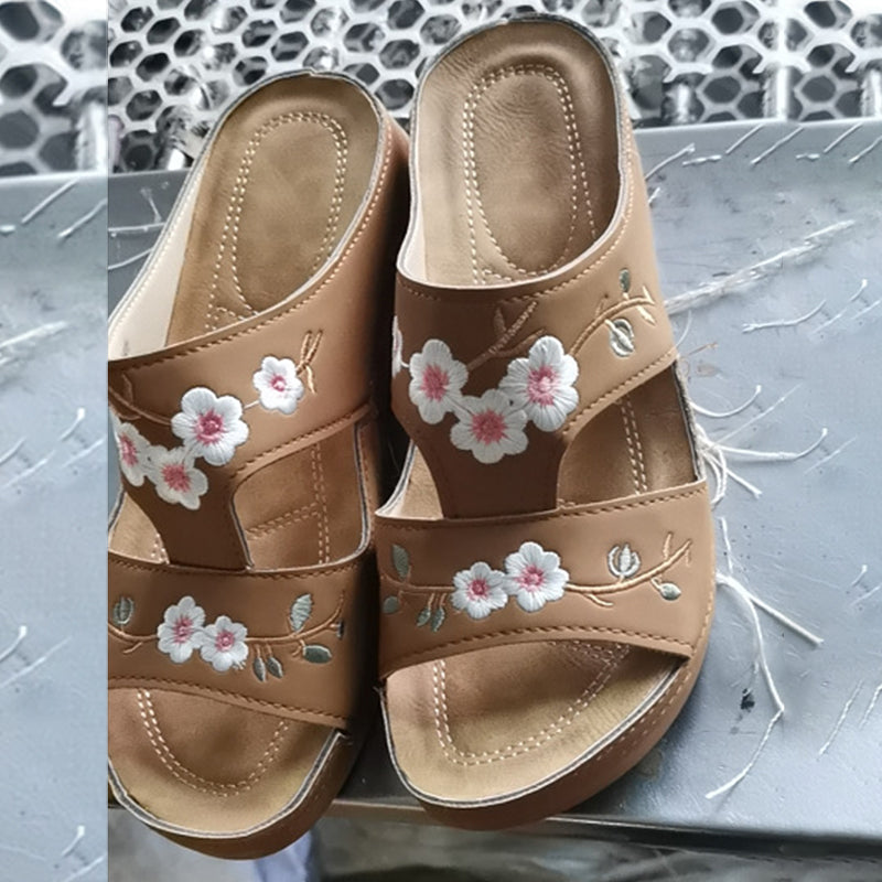"Ortopediska kilsandaler för kvinnor med broderat blommönster, bruna och böjda sulor för överlägsen fotkomfort."
