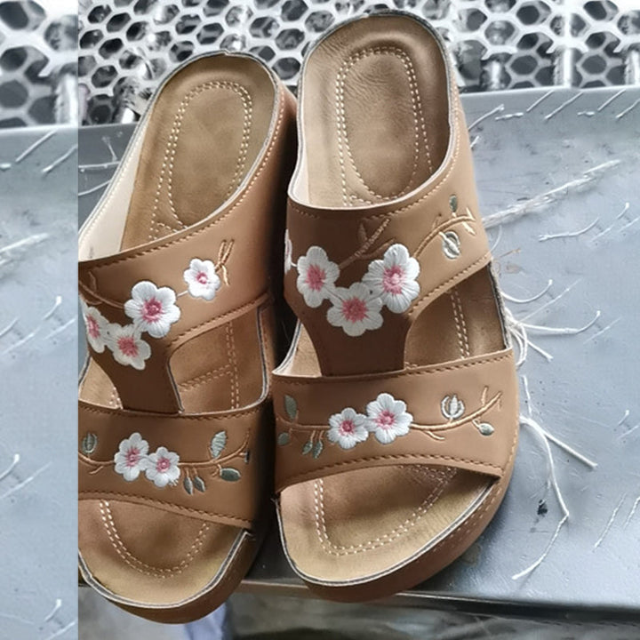 "Ortopediska kilsandaler för kvinnor med broderat blommönster, bruna och böjda sulor för överlägsen fotkomfort."