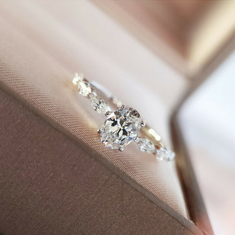 "Oval förlovningsring för damer i silver och guld med moissanite-sten och diamantbesatta band, elegant accessoar."