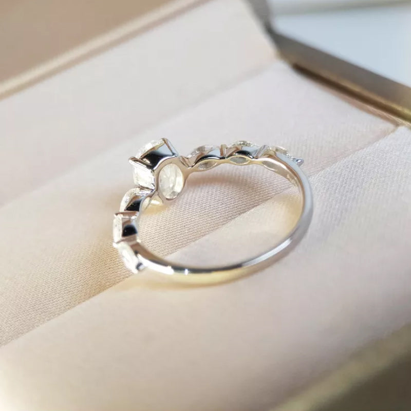 "Oval förlovningsring för damer i silver och guld med moissanite-sten och diamantbesatta band, elegant accessoar."