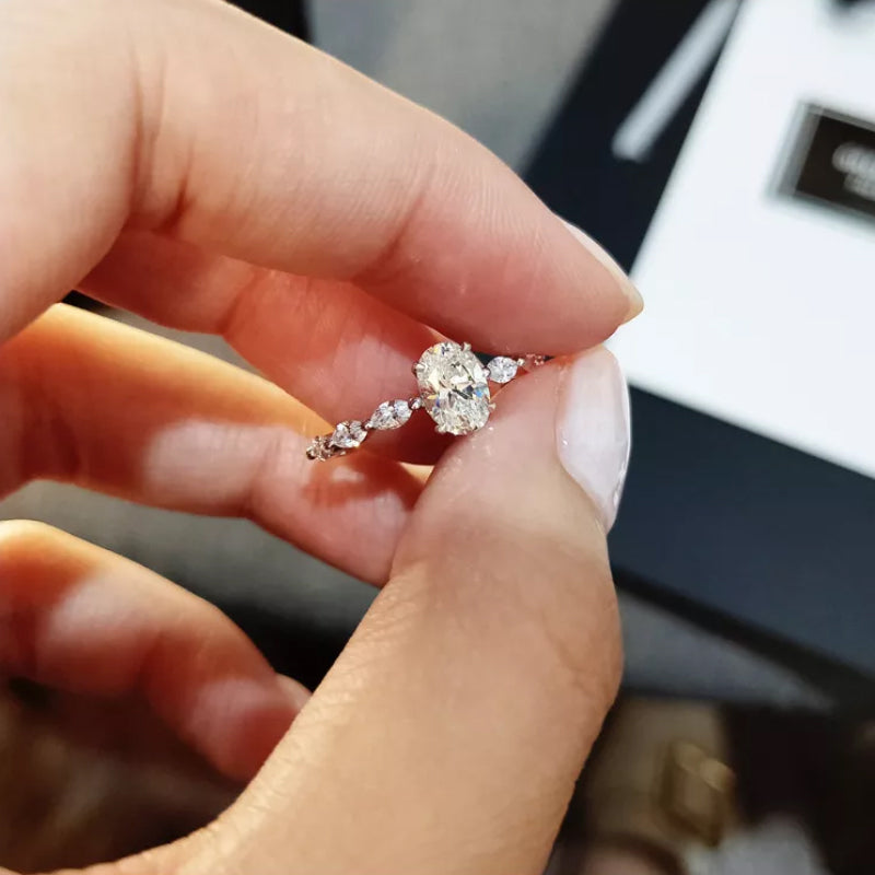 "Oval förlovningsring för damer i silver och guld med moissanite-sten och diamantbesatta band, elegant accessoar."