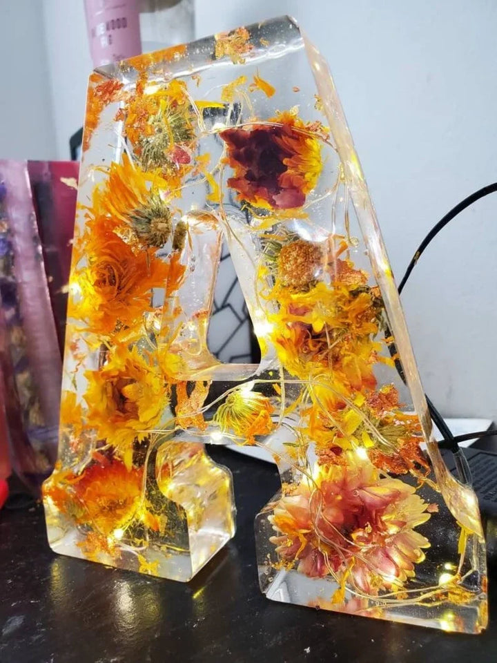 Stämningsfull blomsterlampa i harts, handgjord med valfri bokstav och LED-ljus, vacker inredningsdetalj.
