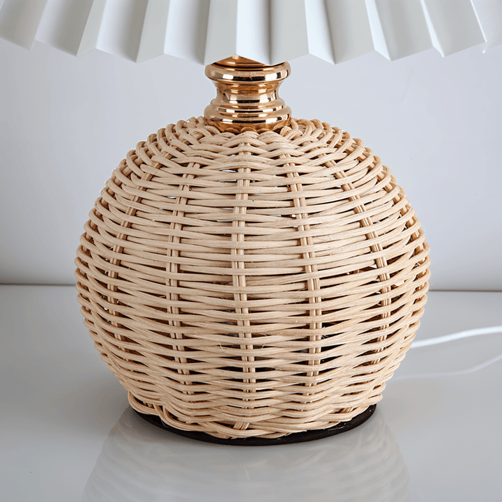 Varm belysning från plisserad bordslampa med retro rotting, perfekt för vardagsrum.
