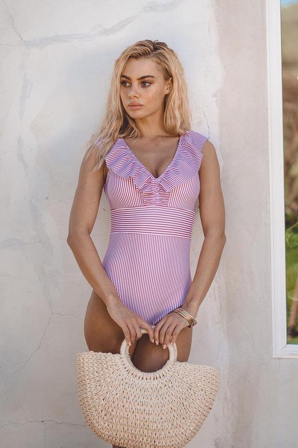 Damer poserar i randig retro baddräkt. Tidlös one-piece badkläder, perfekt för sommarens strandmode.