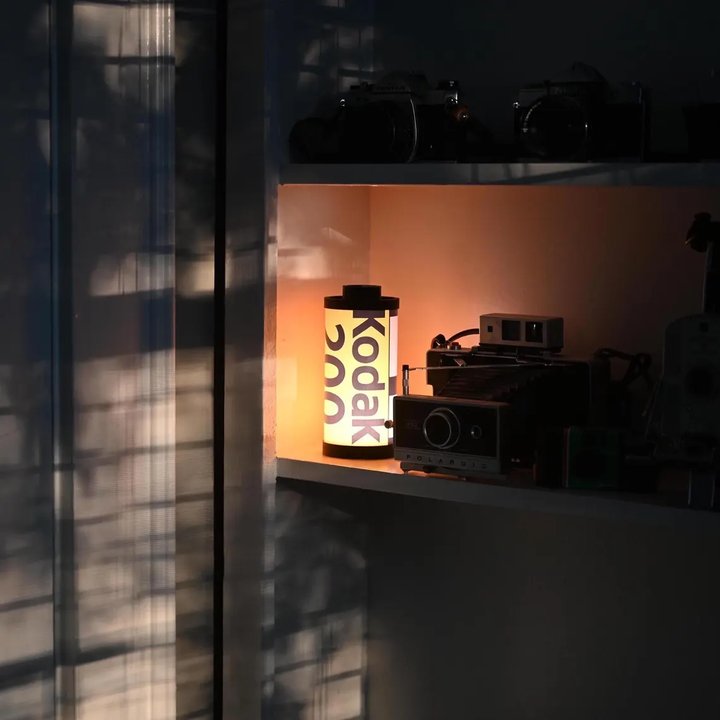 RetroGlow filmkassettlampa på ett bord, sprider mysigt sken. En unik retro designlampa för vintageälskare.
