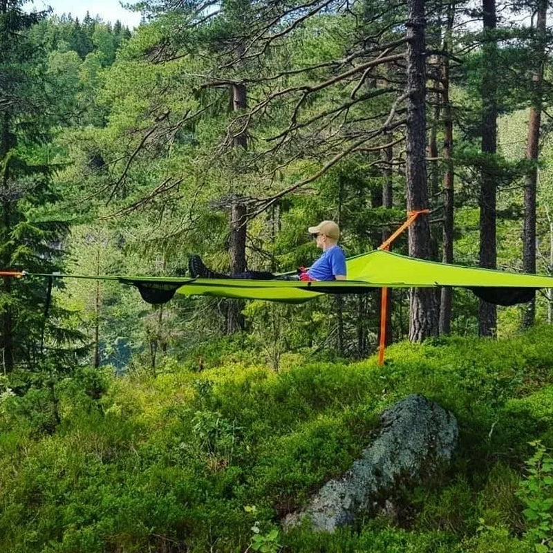 "Robust grön och svart nylonhängmatta för flera personer, perfekt för camping och utflykter, i naturlig miljö."