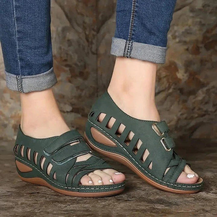 "Romerska dam sandaler med fiskmun, dekorativa skärningar och hög kilklack i elegant beige, framifrån."