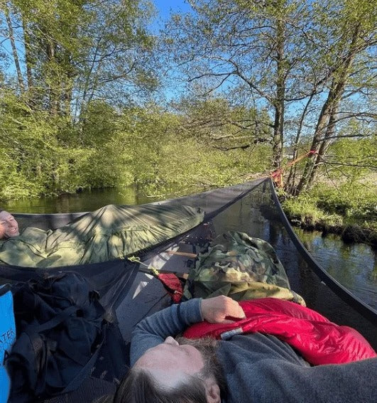 Familj njuter av friluftsliv i en grön triangelhängmatta, en bärbar campinglösning.