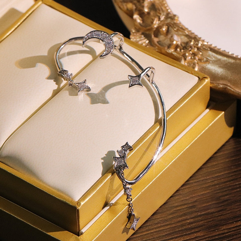 "Silver öronklämma med måne och stjärnor, elegant damaccessoar, zirkondetaljer som fångar ljuset."