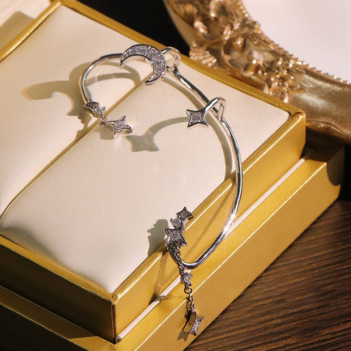 "Silver öronklämma med måne och stjärnor, elegant damaccessoar, zirkondetaljer som fångar ljuset."