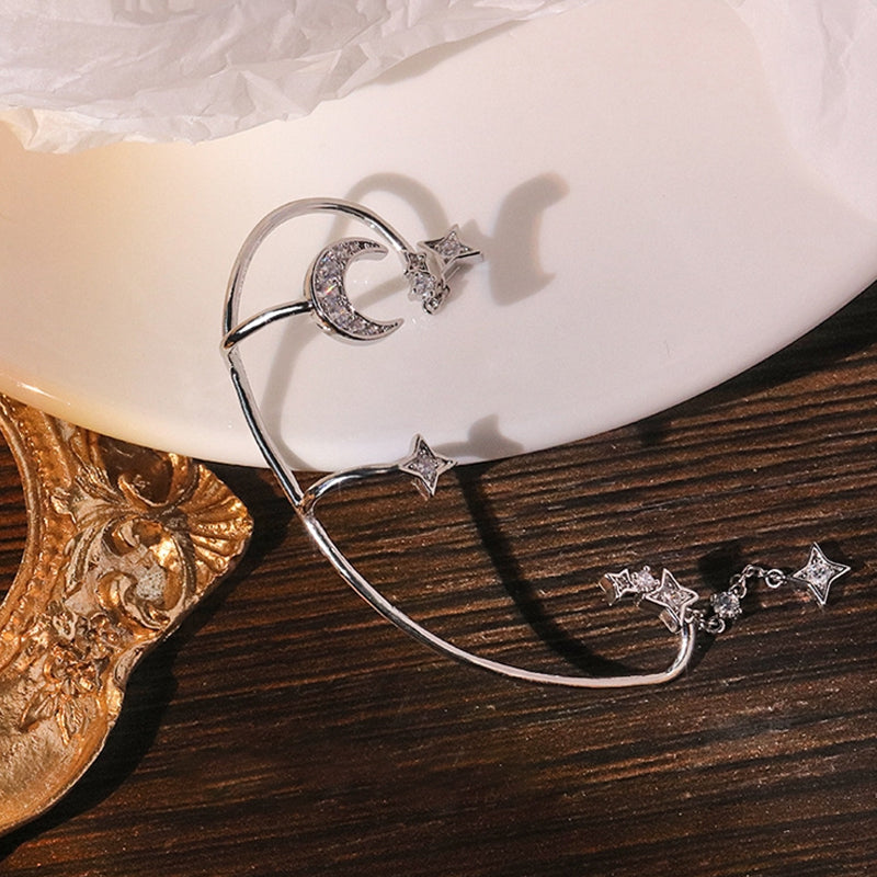 "Silver öronklämma med måne och stjärnor, elegant damaccessoar, zirkondetaljer som fångar ljuset."