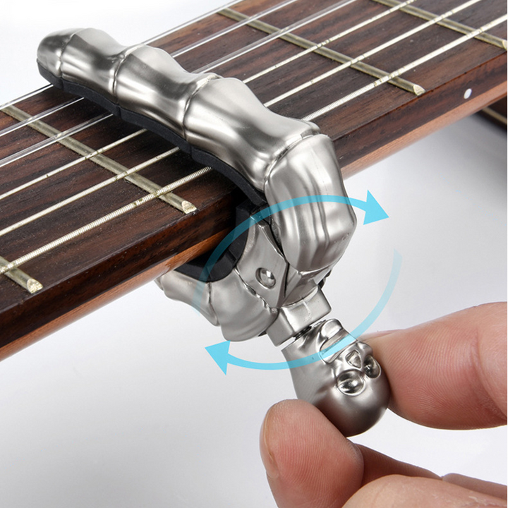 Skalleformad gitarrcapo i metall med unik design, perfekt för akustiska och elektriska gitarrer, finns i flera färger.