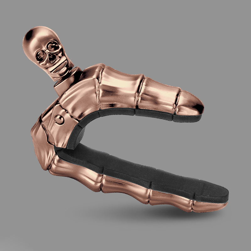 Skalleformad gitarrcapo i metall med unik design, perfekt för akustiska och elektriska gitarrer, finns i flera färger.