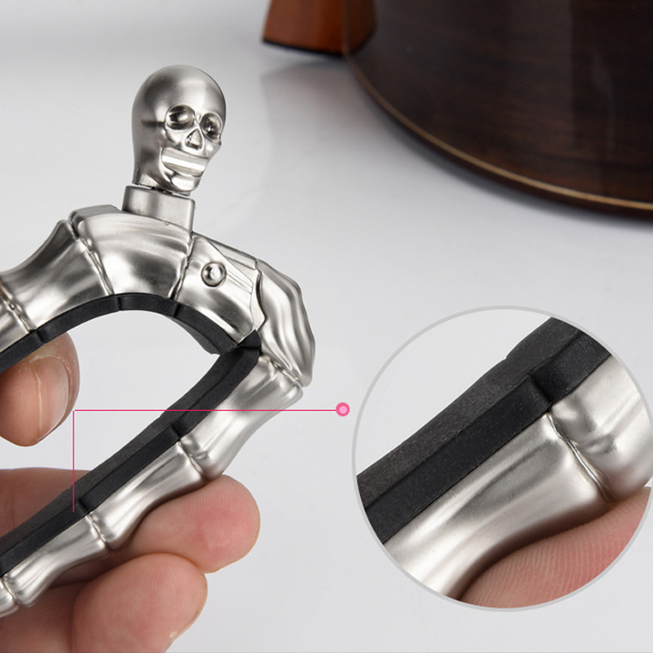 Skalleformad gitarrcapo i metall med unik design, perfekt för akustiska och elektriska gitarrer, finns i flera färger.