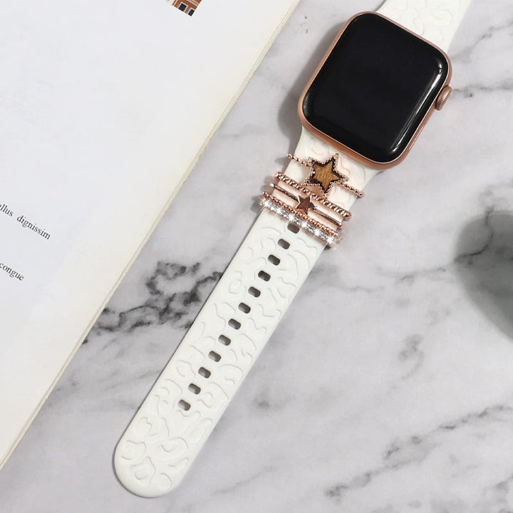 "Smartklockband med dekorativa metallringar i gyllene leopardmönster och roséguldstjärnor, elegant stilaccessoar."