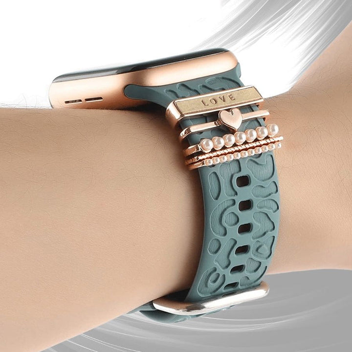 "Smartklockband med dekorativa metallringar i gyllene leopardmönster och roséguldstjärnor, elegant stilaccessoar."