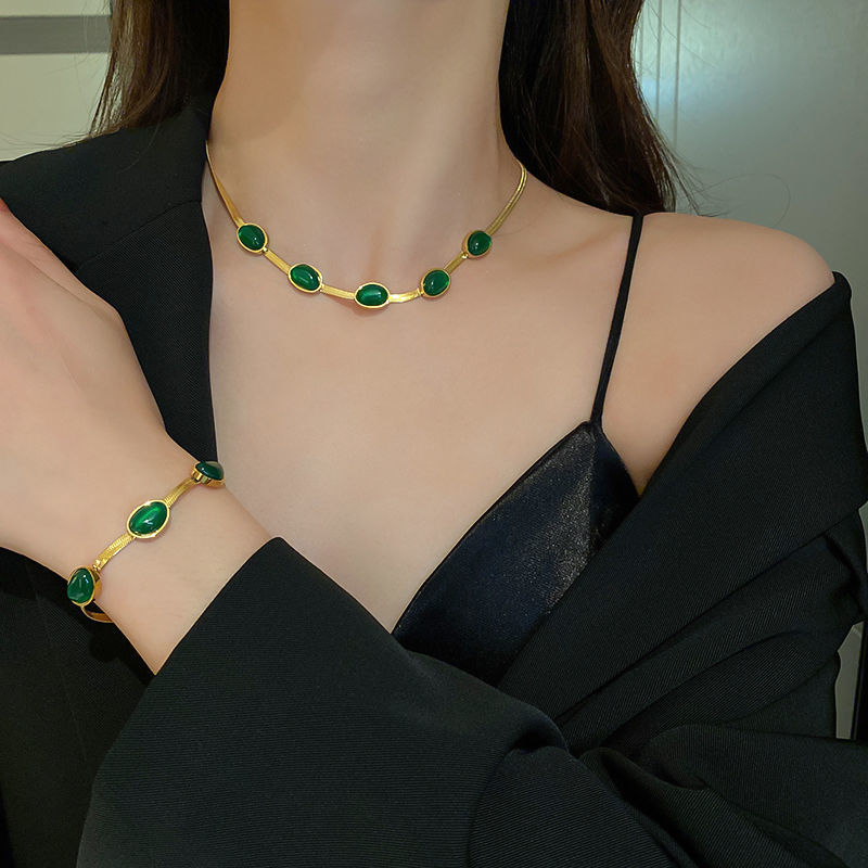 "Smycke i titanstål för kvinnor, smaragdberlock: elegant halsband och armband i grönt för stil och sofistikation."