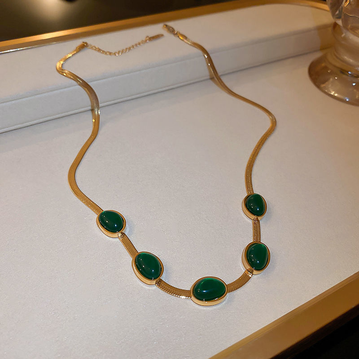 "Smycke i titanstål för kvinnor, smaragdberlock: elegant halsband och armband i grönt för stil och sofistikation."