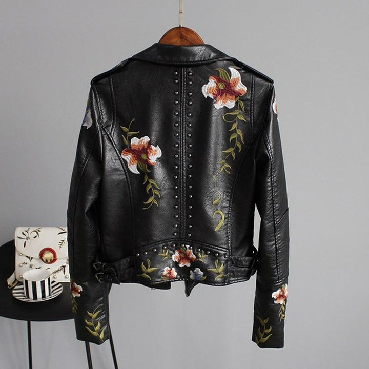 Detaljbild på trendig blommönstrad dam-bikerjacka med dragkedjor och nitar, ett fashionabelt val för både vår- och höstmode.
