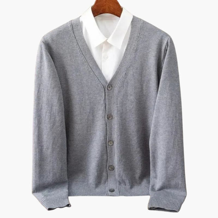 Elegant grå herrkofta. Stickad med V-ringning, knappar. Komfortabelt vardagsplagg för stilmedveten herrmode.
