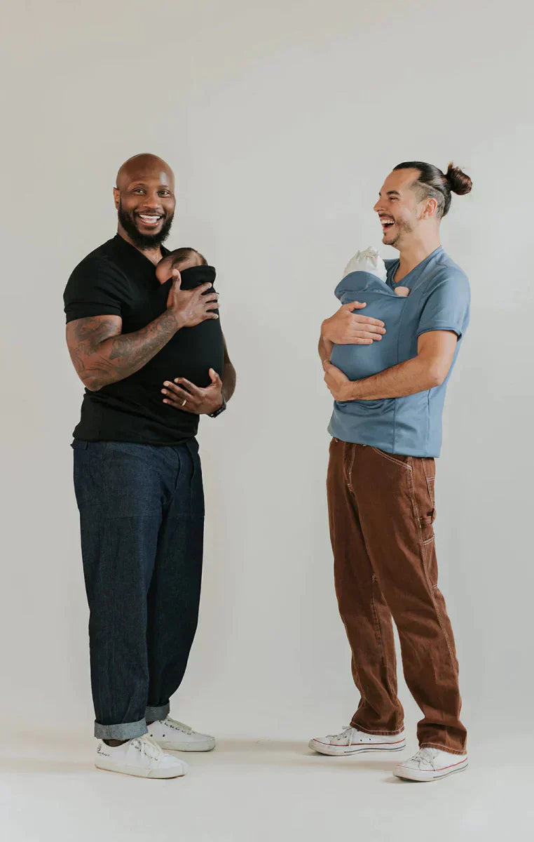 En glad baby sover tryggt och bekvämt i den mysiga och säkra CarrySeed Tee bärselen med snugfit.