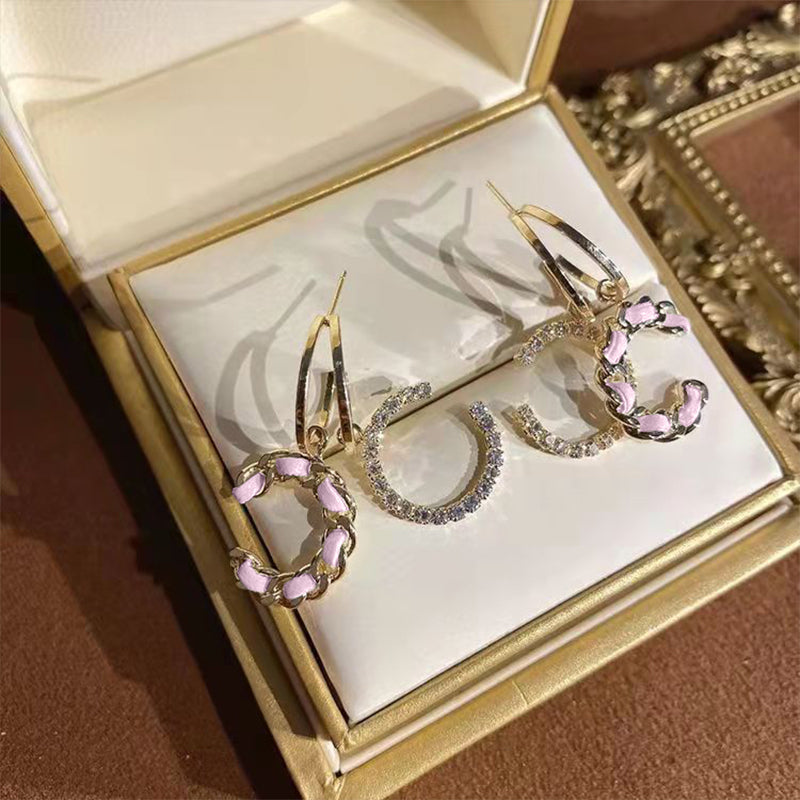 "Stilrena kvinnors silverörhängen med glittrande kristaller i dubbel 'C' design, eleganta och tidlösa accessoarer."
