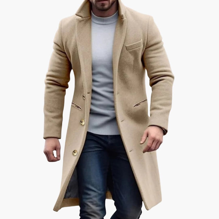 Grå lång herrkappa med klassisk knappslå, stilrent ytterplagg för elegant höst- och vintermode.