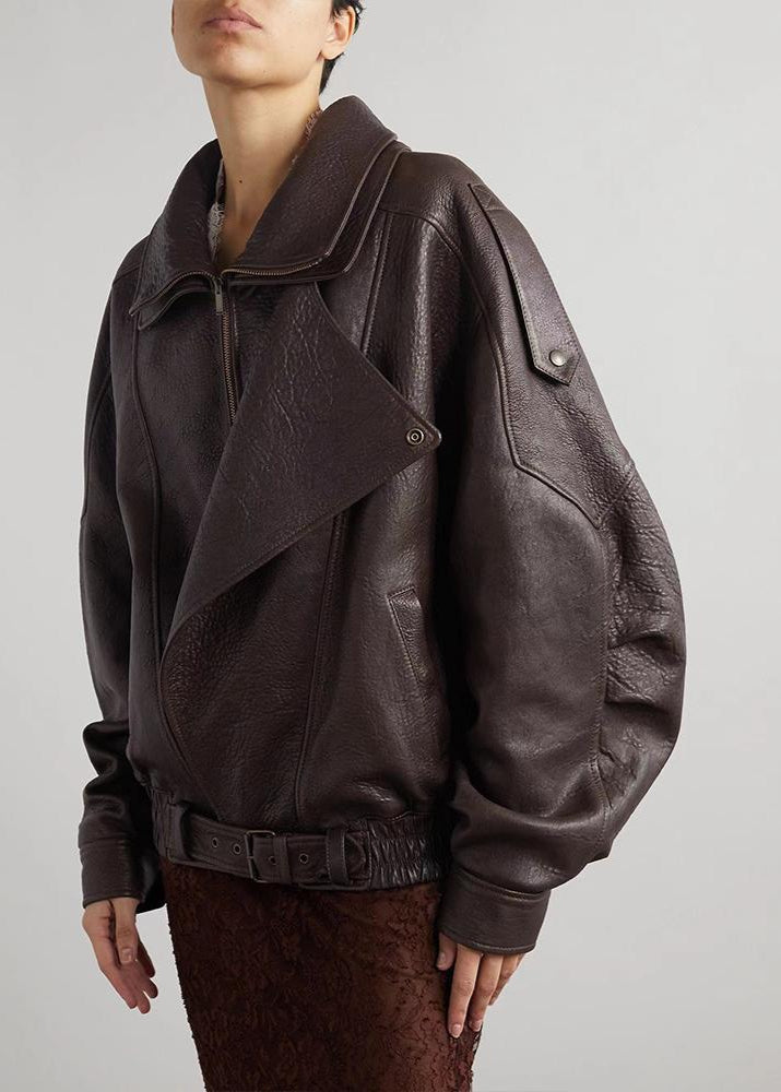 Kvinnlig modell bär svart oversized läderbomberjacka med markerat bälte, sidoprofil.