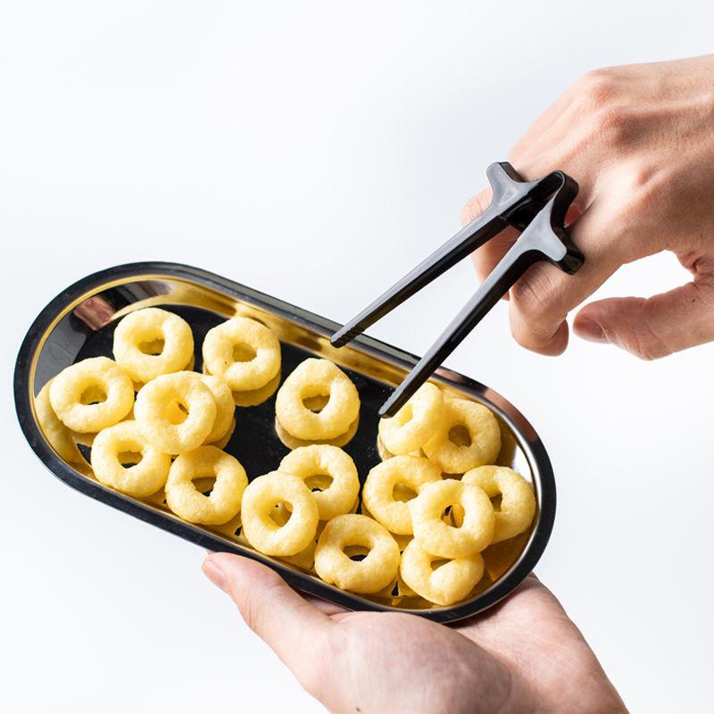 "Svart plastätpinne för snacks, innovativ design för rena händer och multitasking, perfekt för köket eller på språng."
