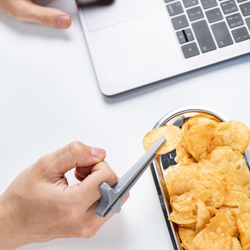 "Svart plastätpinne för snacks, innovativ design för rena händer och multitasking, perfekt för köket eller på språng."