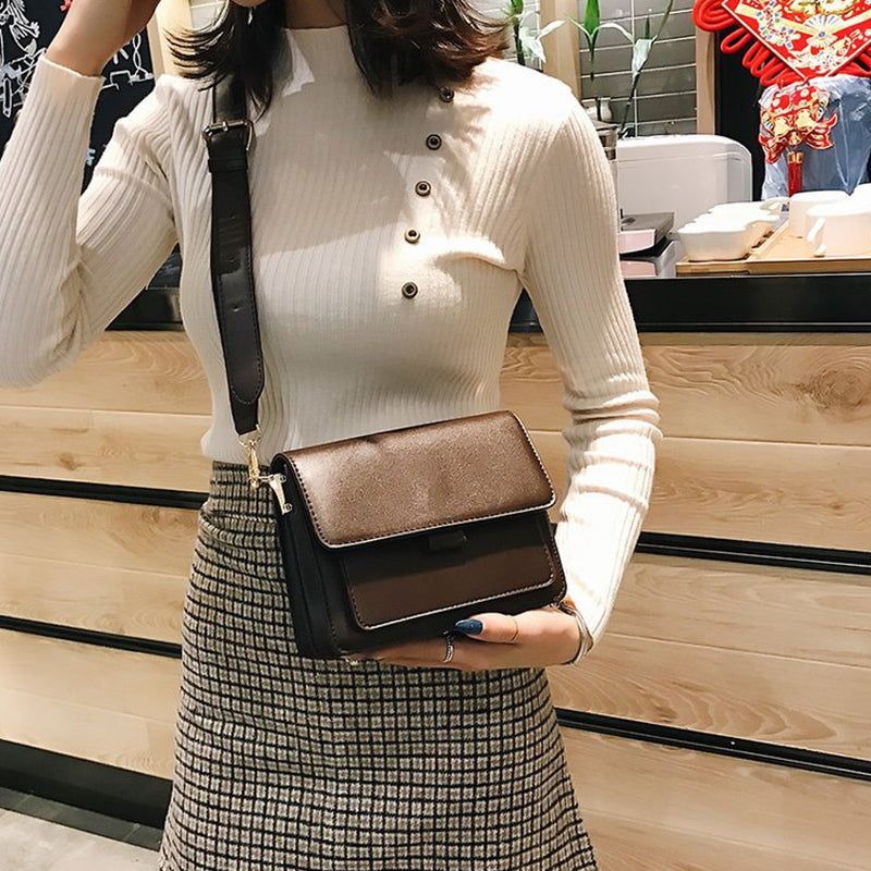 Svart retro crossbody väska i konstläder med minimalistisk design och flera fack för damaccessoarer.
