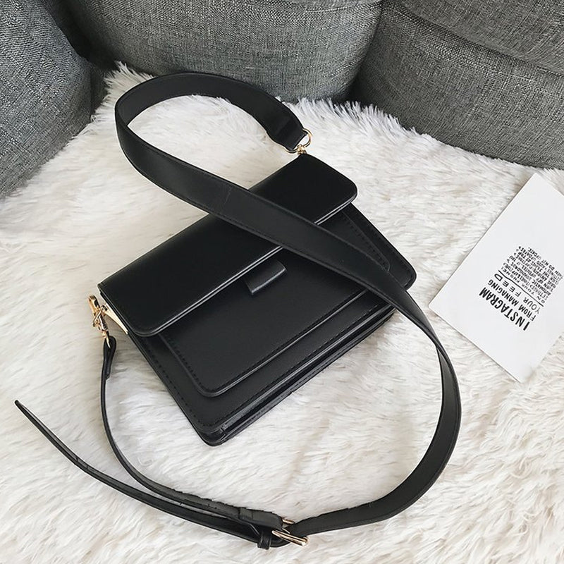 Svart retro crossbody väska i konstläder med minimalistisk design och flera fack för damaccessoarer.