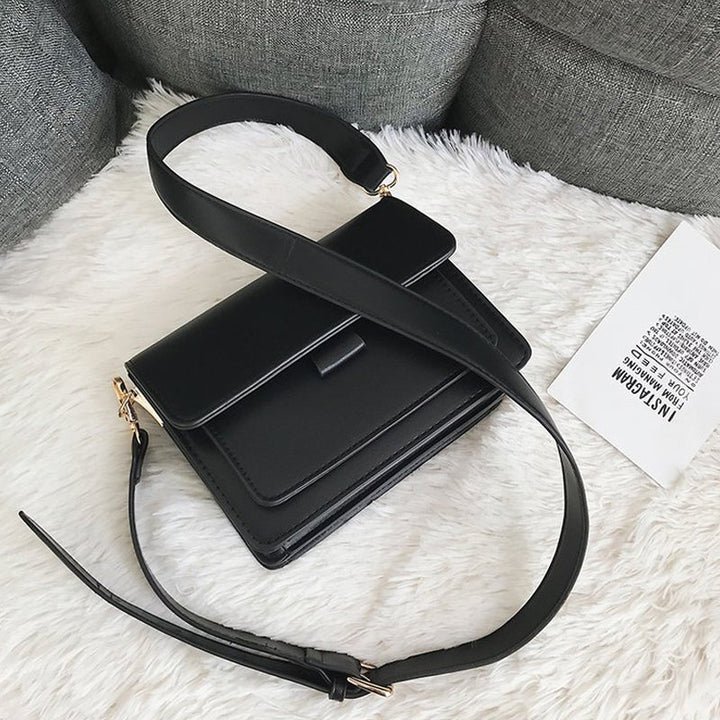 Svart retro crossbody väska i konstläder med minimalistisk design och flera fack för damaccessoarer.