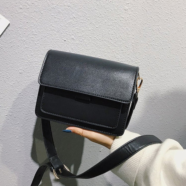 Svart retro crossbody väska i konstläder med minimalistisk design och flera fack för damaccessoarer.