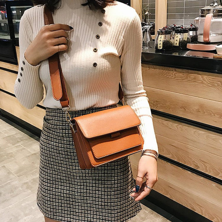 Svart retro crossbody väska i konstläder med minimalistisk design och flera fack för damaccessoarer.