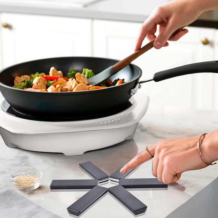 "Svart vikbar silikonplatta, värmeisolerande och halkfri, skyddar köksbord med stil. Perfekt för köks- och tallriksmattor."