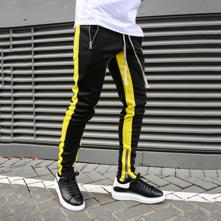 "Svarta herrjoggingbyxor med skinny passform, sidoficka med blixtlås, avsmalnande ben och mjukt polyestermaterial."