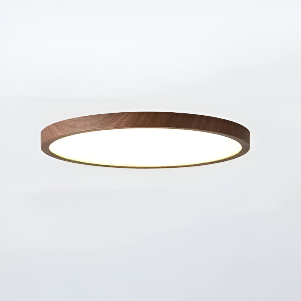Vinklad bild på rund LED taklampa i valnötsträ, dess ultratunna profil framhävs.