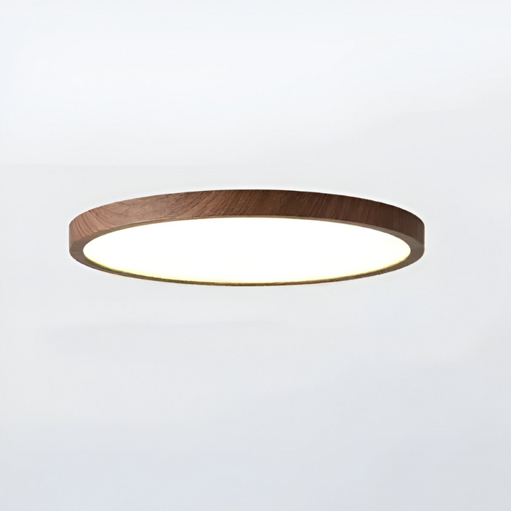 Vinklad bild på rund LED taklampa i valnötsträ, dess ultratunna profil framhävs.