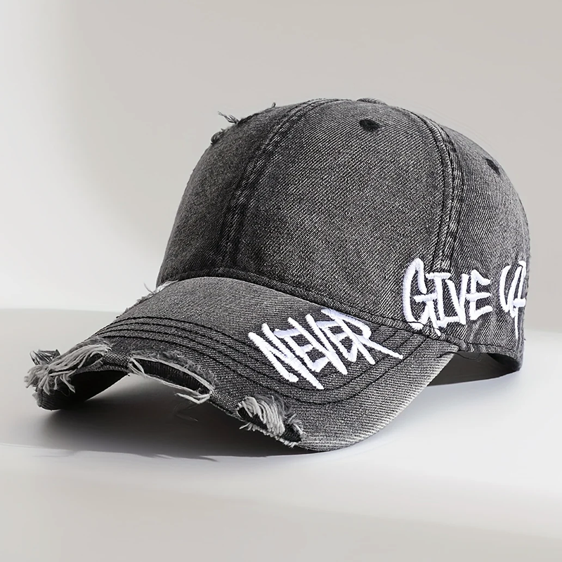 Närbild av en avslappnad baseballkeps i distressed denim med unikt broderi, justerbar och unisex.