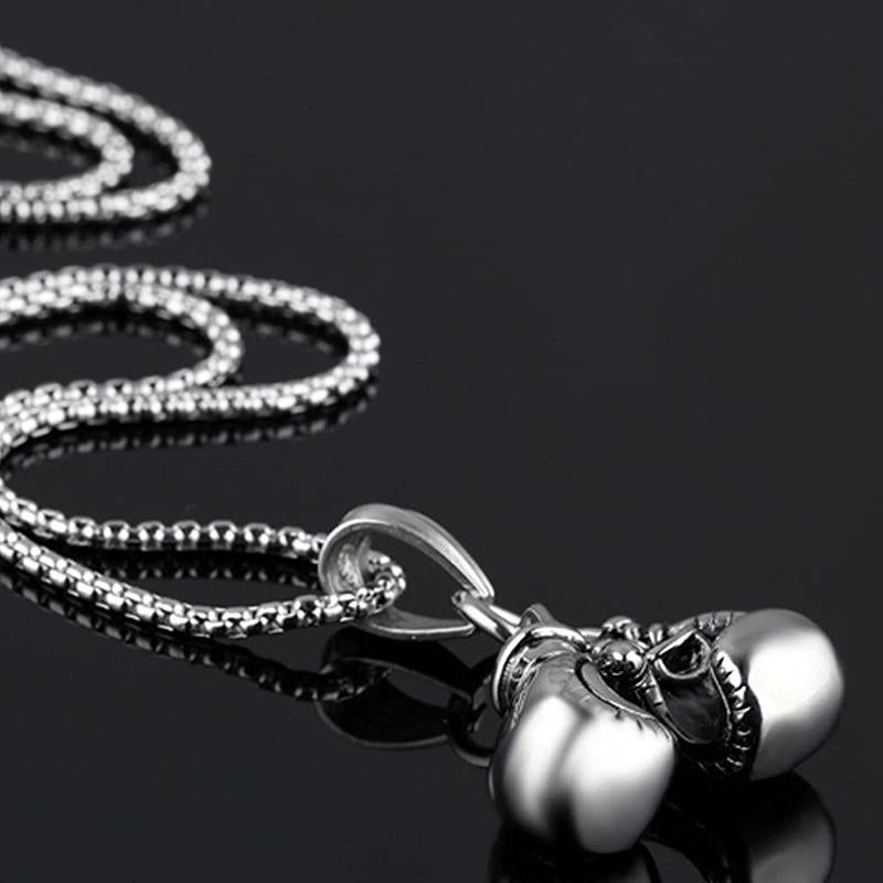 "Unisex boxhandskar halsband i ett glänsande guldigt titanstål, symboliserar styrka och stil för boxningsentusiaster."